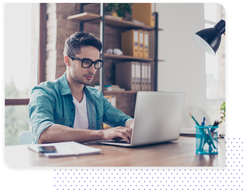 A young man in glasses working on a laptop